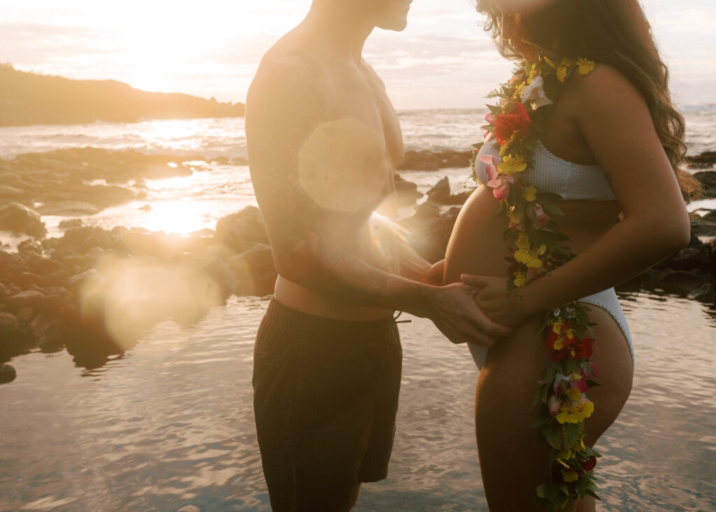 couple on the beach with a glowy sunrise and open lei with flowers